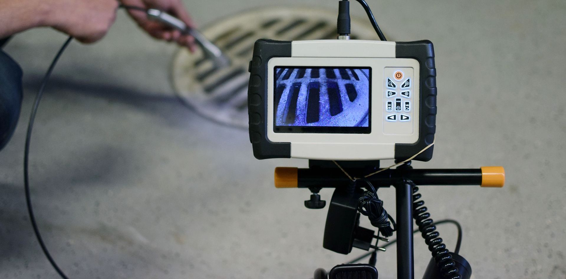 Un homme utilise une caméra pour regarder une plaque d'égout.