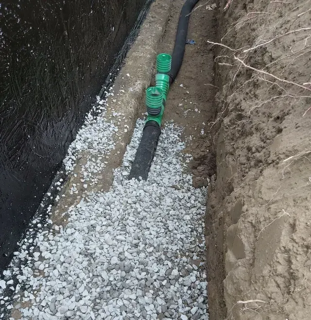 Un tuyau vert est posé dans un tas de gravier