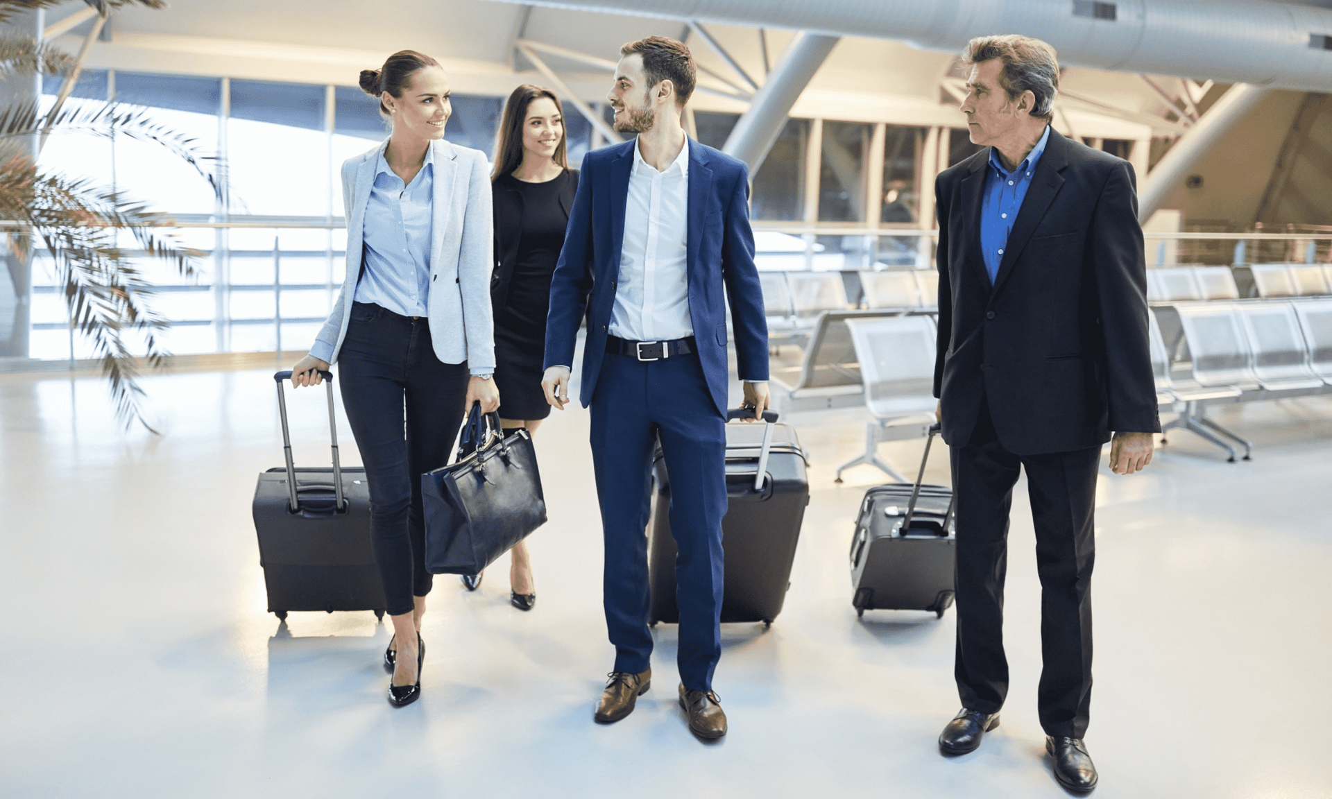 A group of people are walking through an airport with luggage.