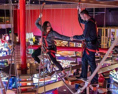 A man and a woman are standing on a ropes course.