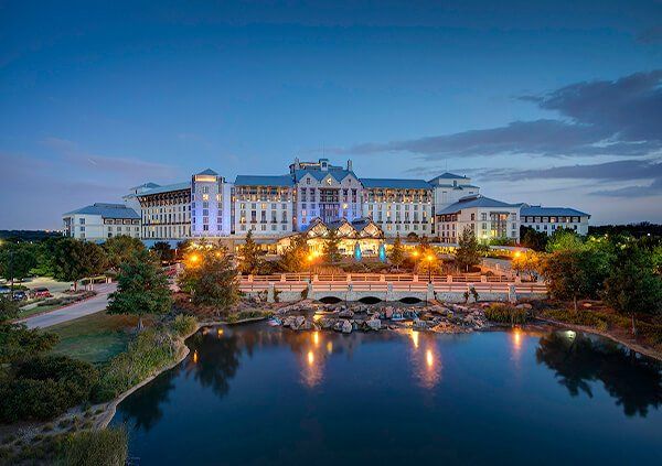 A large hotel with a bridge over a lake at night.