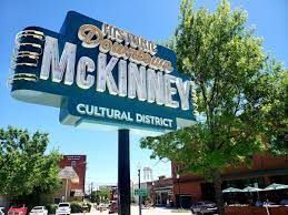 A sign for mckinney cultural district is sitting on the side of a street.