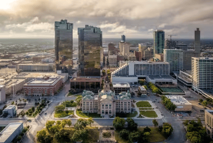 An aerial view of a city with a large building in the middle of the city.