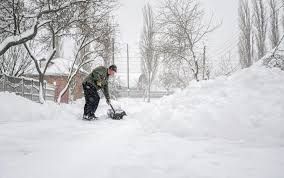 A man is shoveling snow from a driveway with a shovel.