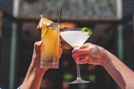 Two people are toasting with two drinks in their hands.