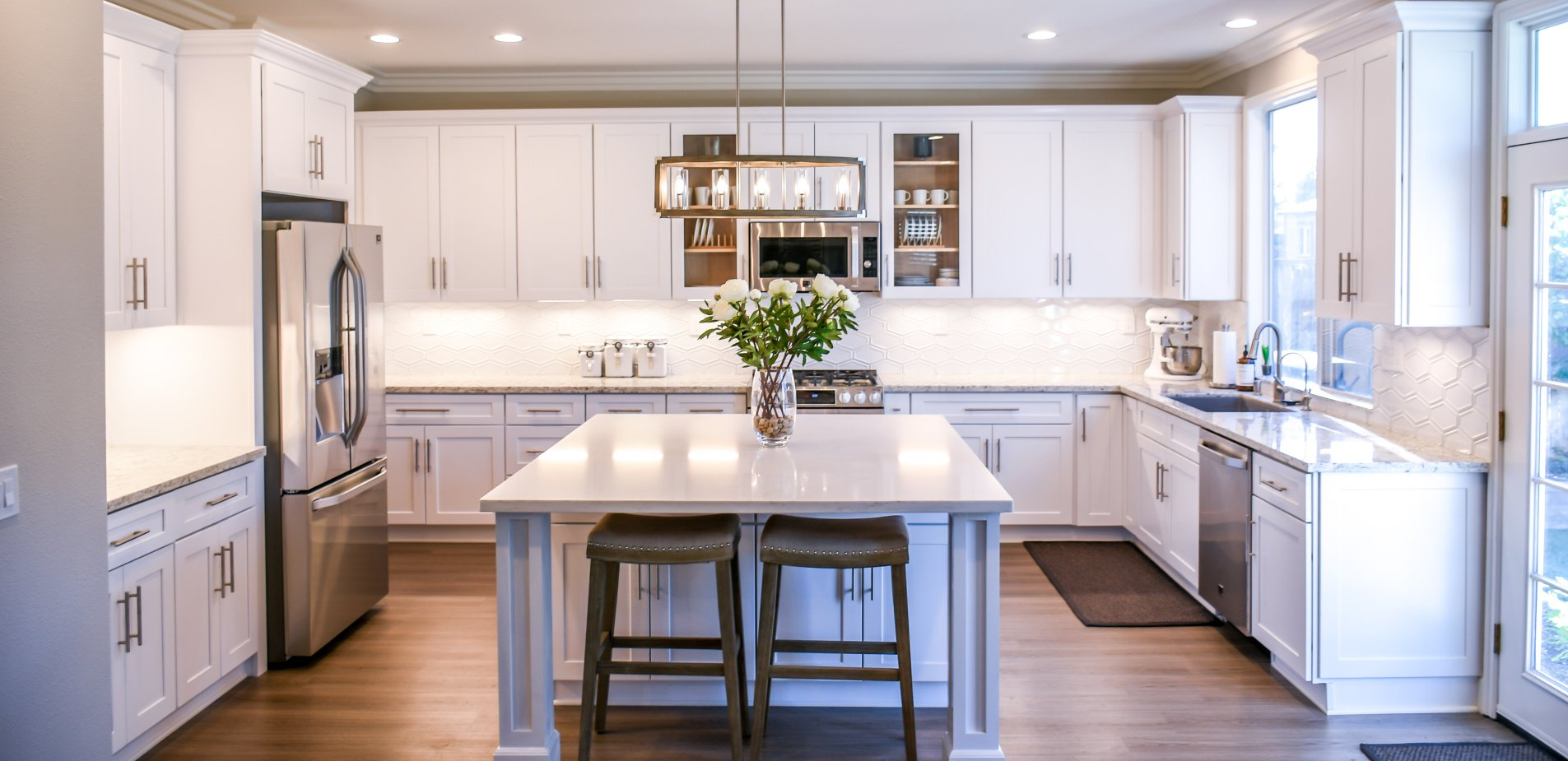 A kitchen with white cabinets , stainless steel appliances , and a large island.