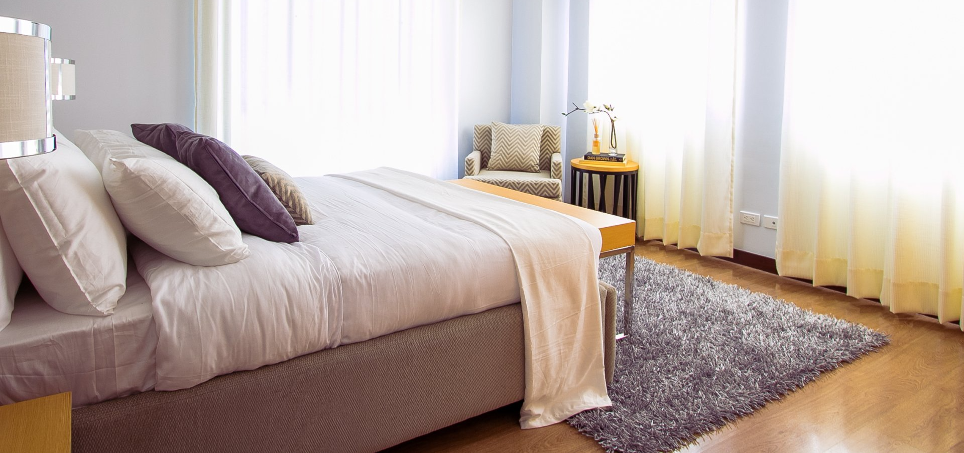 A bedroom with a bed , chair , table and rug.