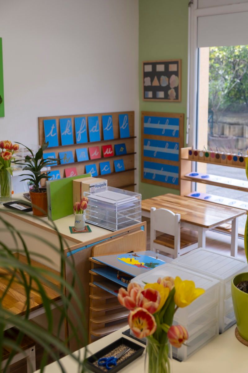 Salle de classe lumineuse avec des cartes d'apprentissage colorées, des tables et des fleurs près de la fenêtre