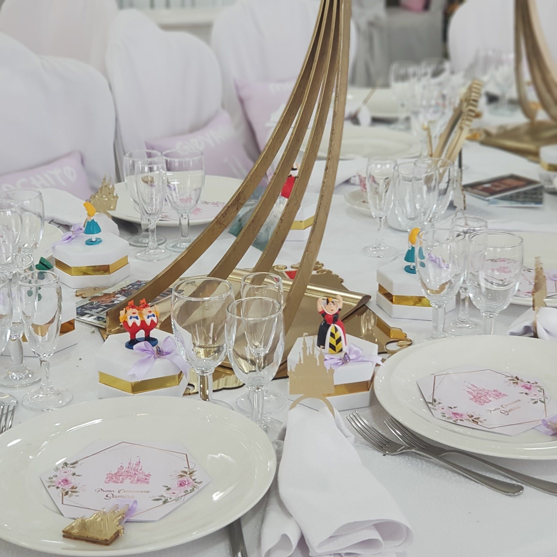 Apparecchiatura della tavola con decorazioni a tema principessa: piatti, bicchieri, centrotavola e bomboniere.