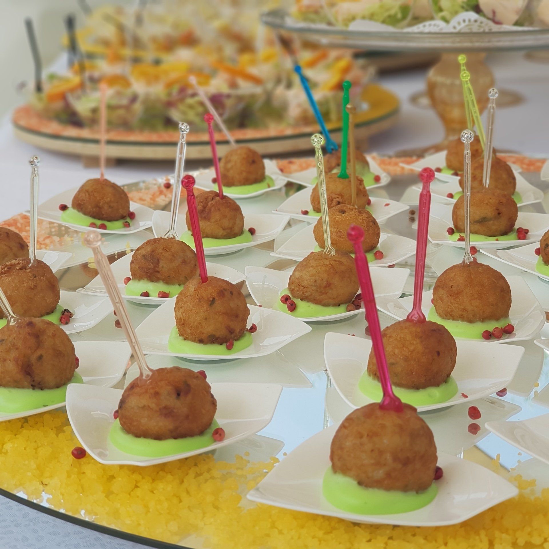Antipasti: Polpette fritte su piccoli piatti con stuzzicadenti, salsa verde chiaro e granella.