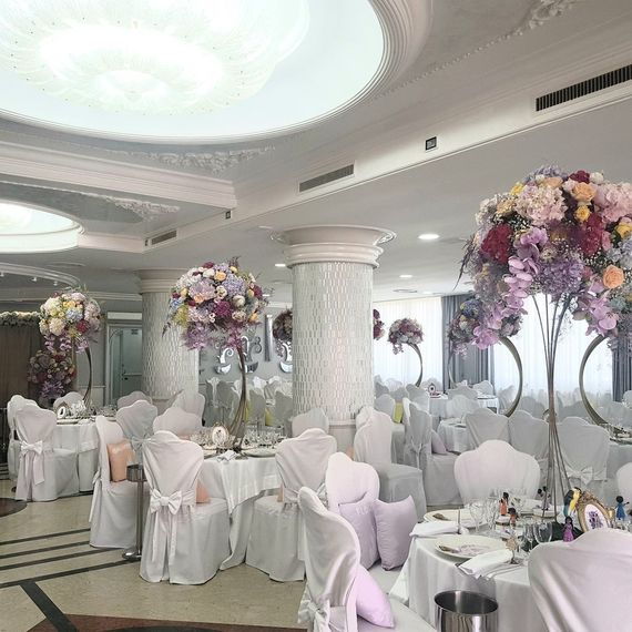 Elegante ricevimento di nozze con centrotavola floreali, sedie e tavoli bianchi.