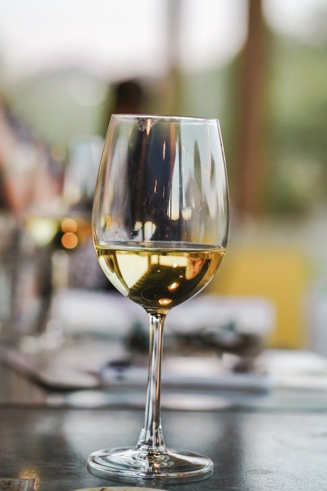 Un calice di vino bianco su un tavolo, con uno sfondo sfocato.