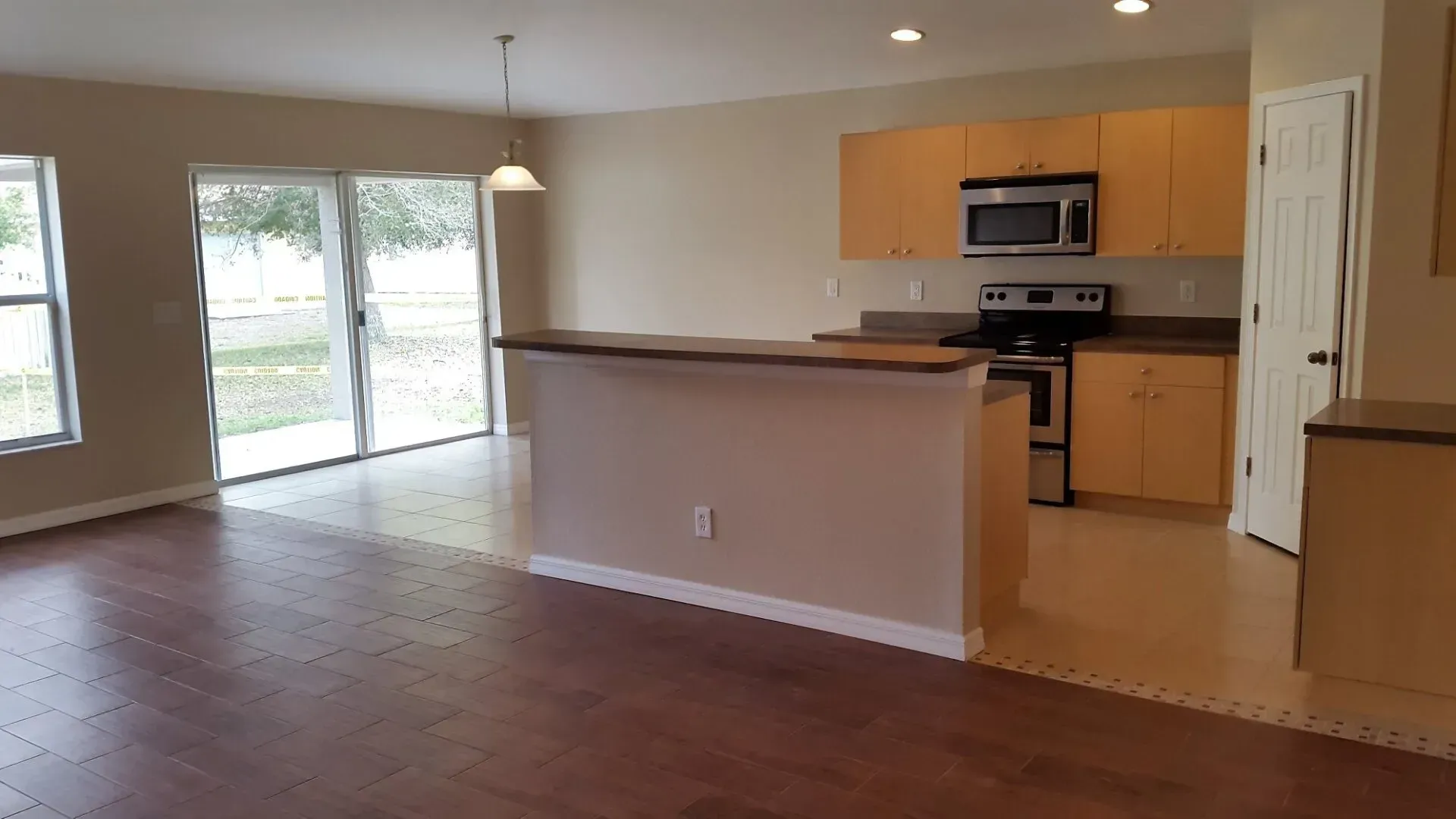 Interior with kitchen, dining area, and living space; hardwood floors and tan walls.