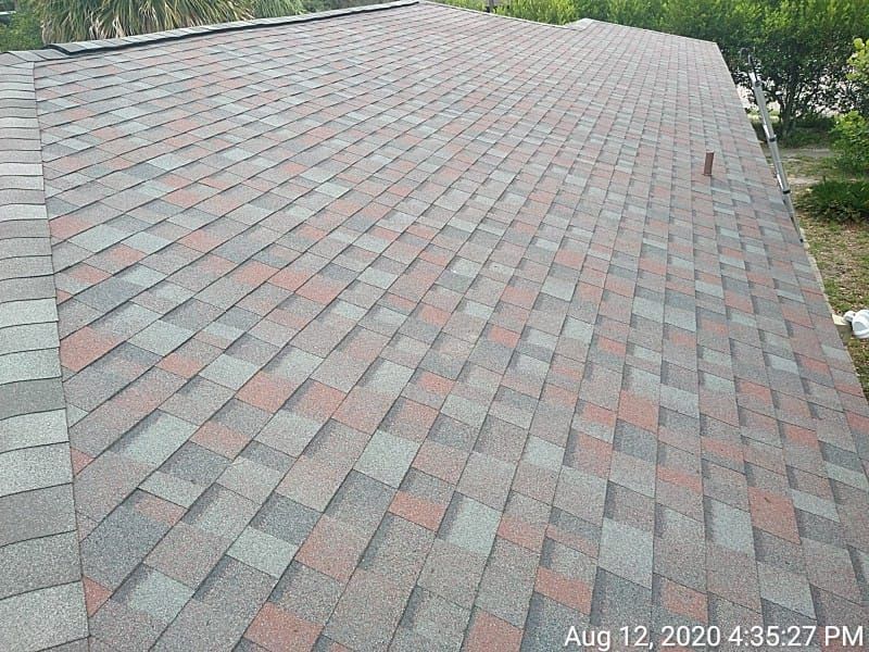 Asphalt shingle roof with gray, brown, and red tones, covering a building.