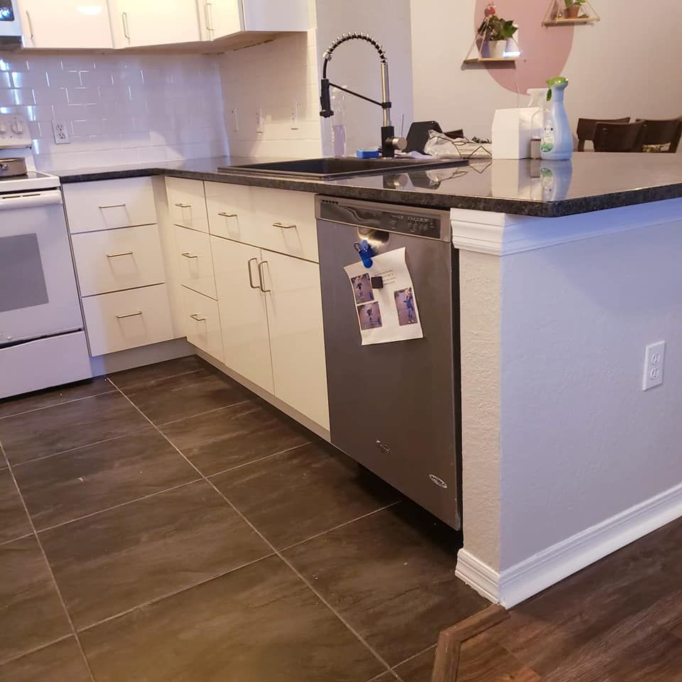 Kitchen with white cabinets, dark countertops, stainless steel appliances, and dark tile flooring.
