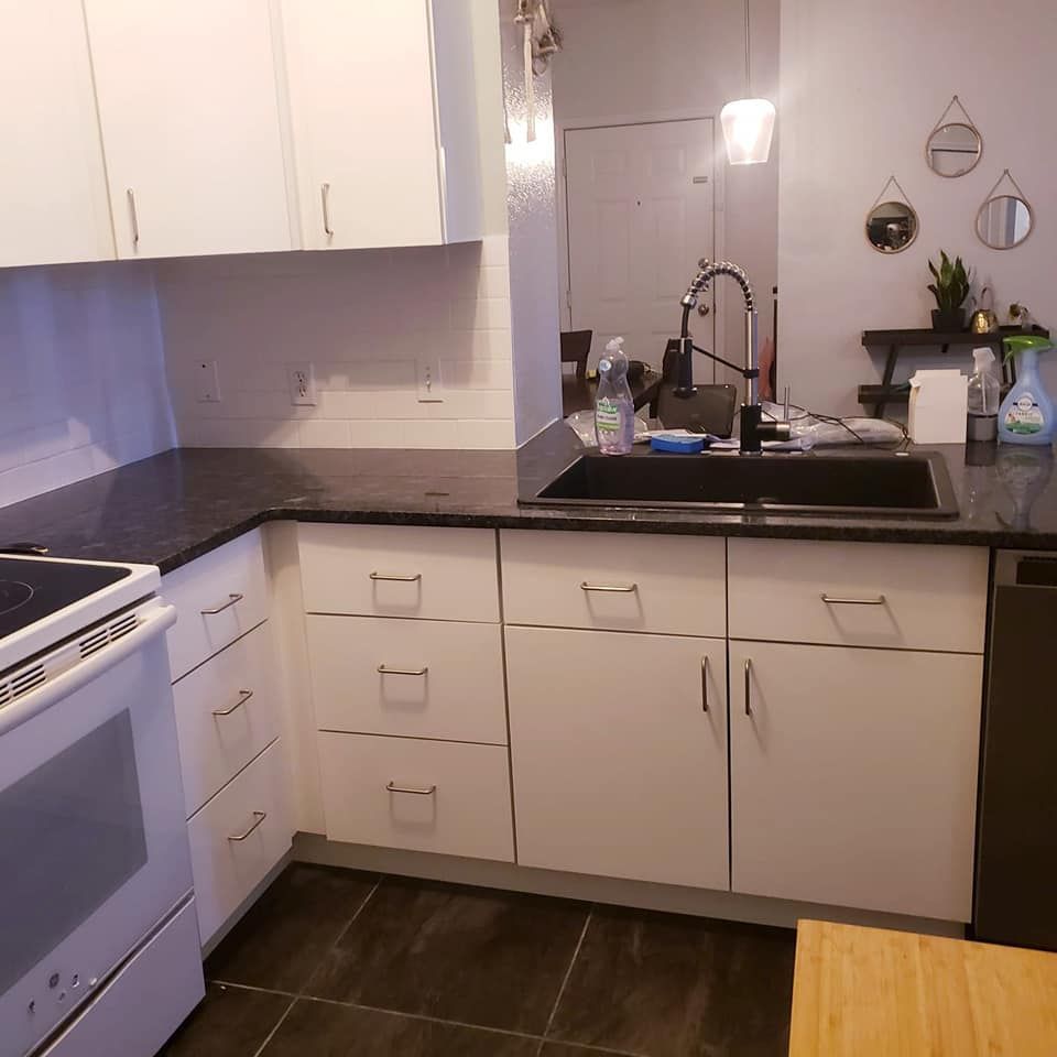 White kitchen cabinets and appliances with black countertops.