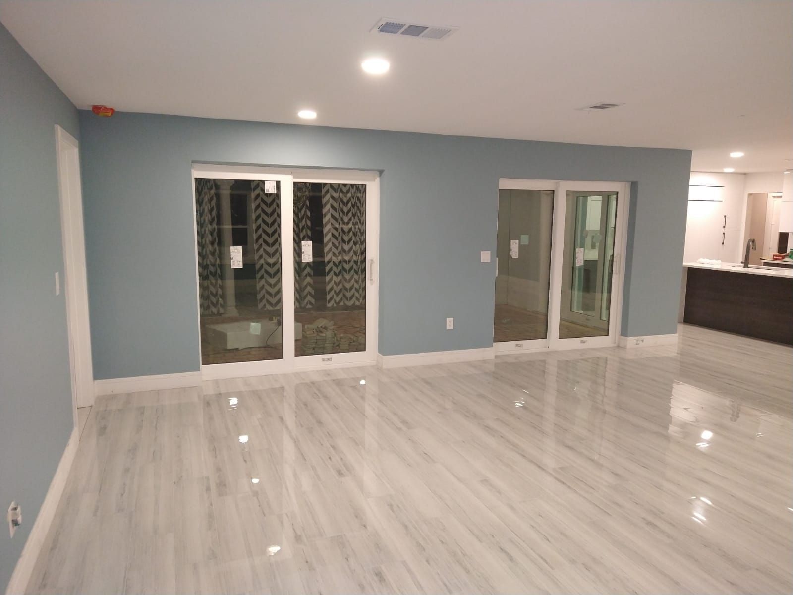 Empty room with blue walls, sliding glass doors, and light gray marble-look flooring.