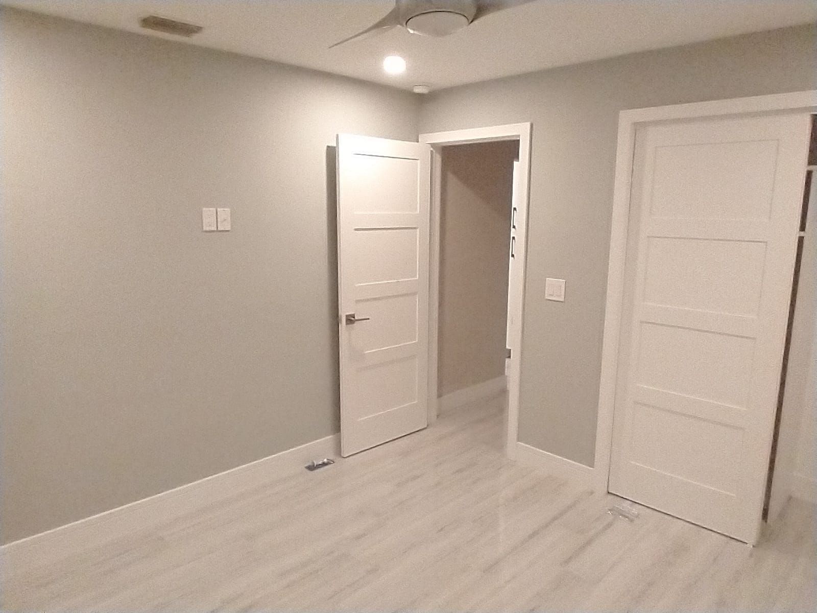 Bedroom with light gray walls, white doors, and light wood-look flooring.