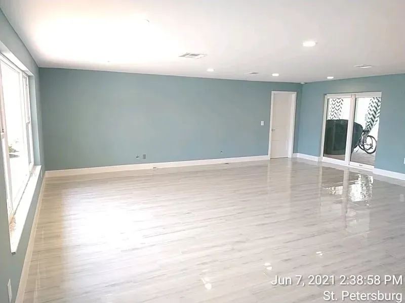 Empty room with blue-grey walls, white tile floor, and sliding glass doors.