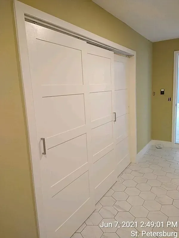 White sliding doors, modern design, against pale yellow wall, handle visible.