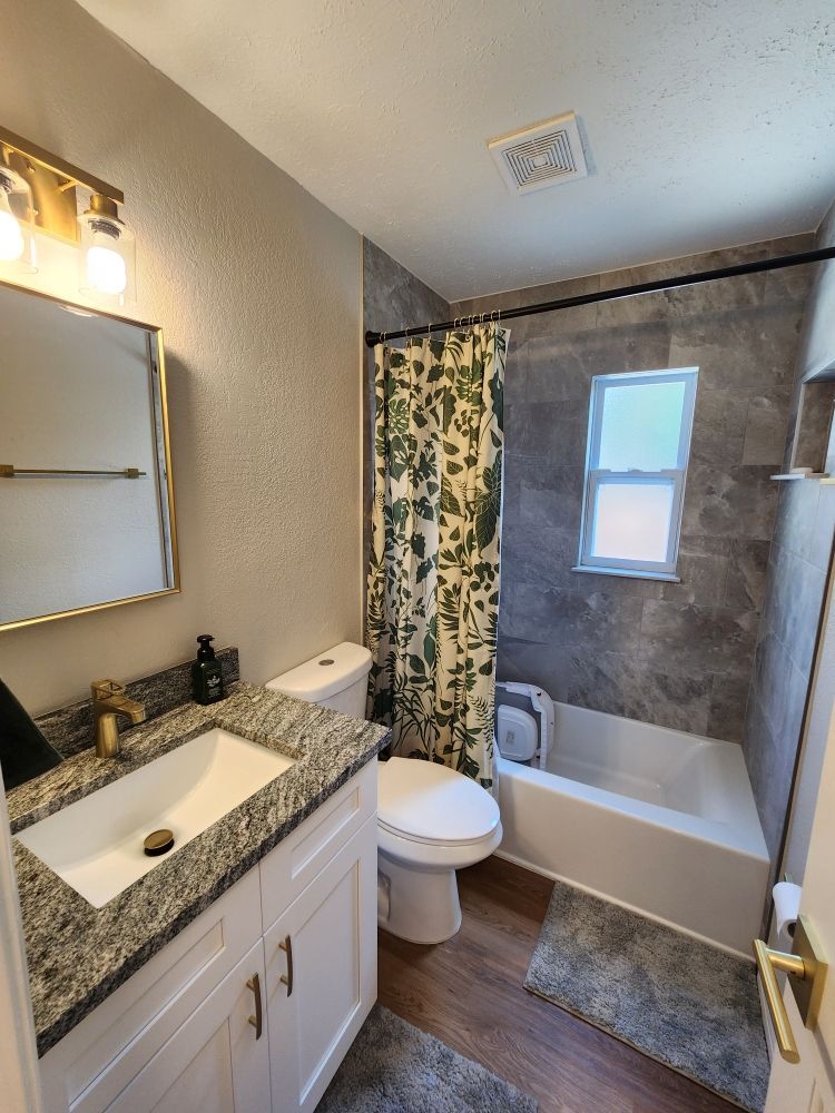 Bathroom with white vanity, gray countertop, and patterned shower curtain.
