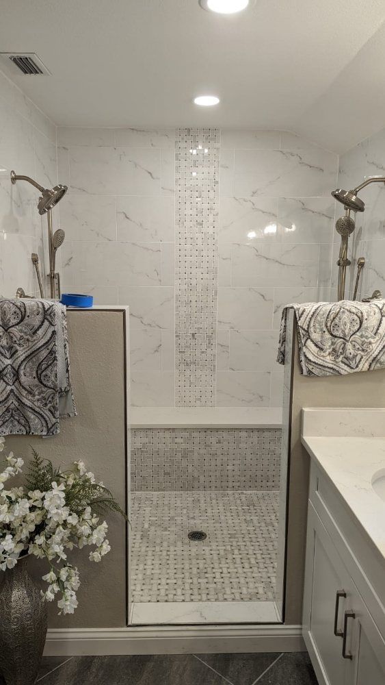 Modern bathroom with dual showerheads, marble tile, and built-in bench.