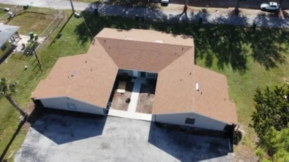 Aerial view of a brown-roofed building with a central courtyard and surrounding parking area.