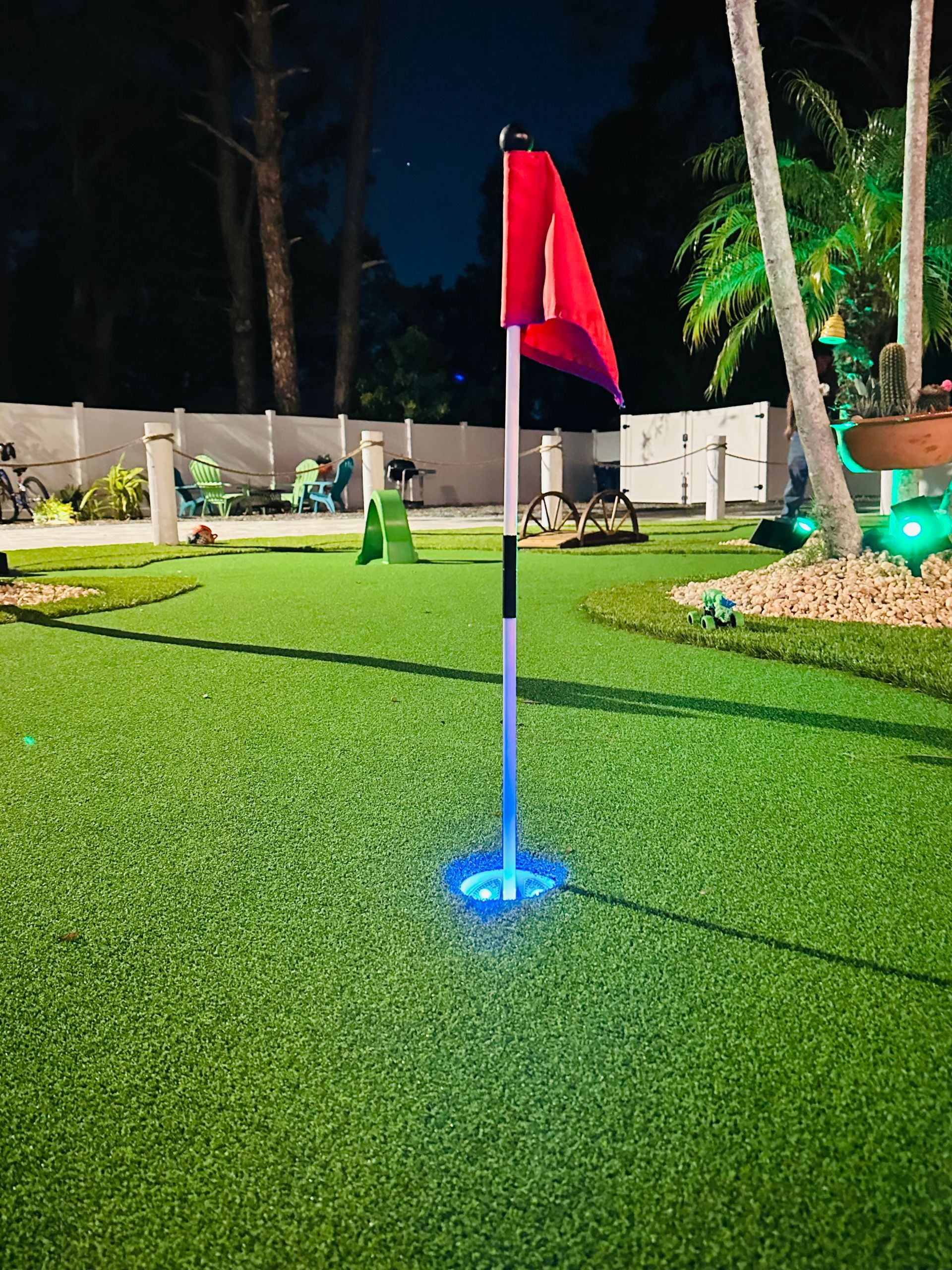 Modern house exterior with green lawn, wooden deck, and landscaping.