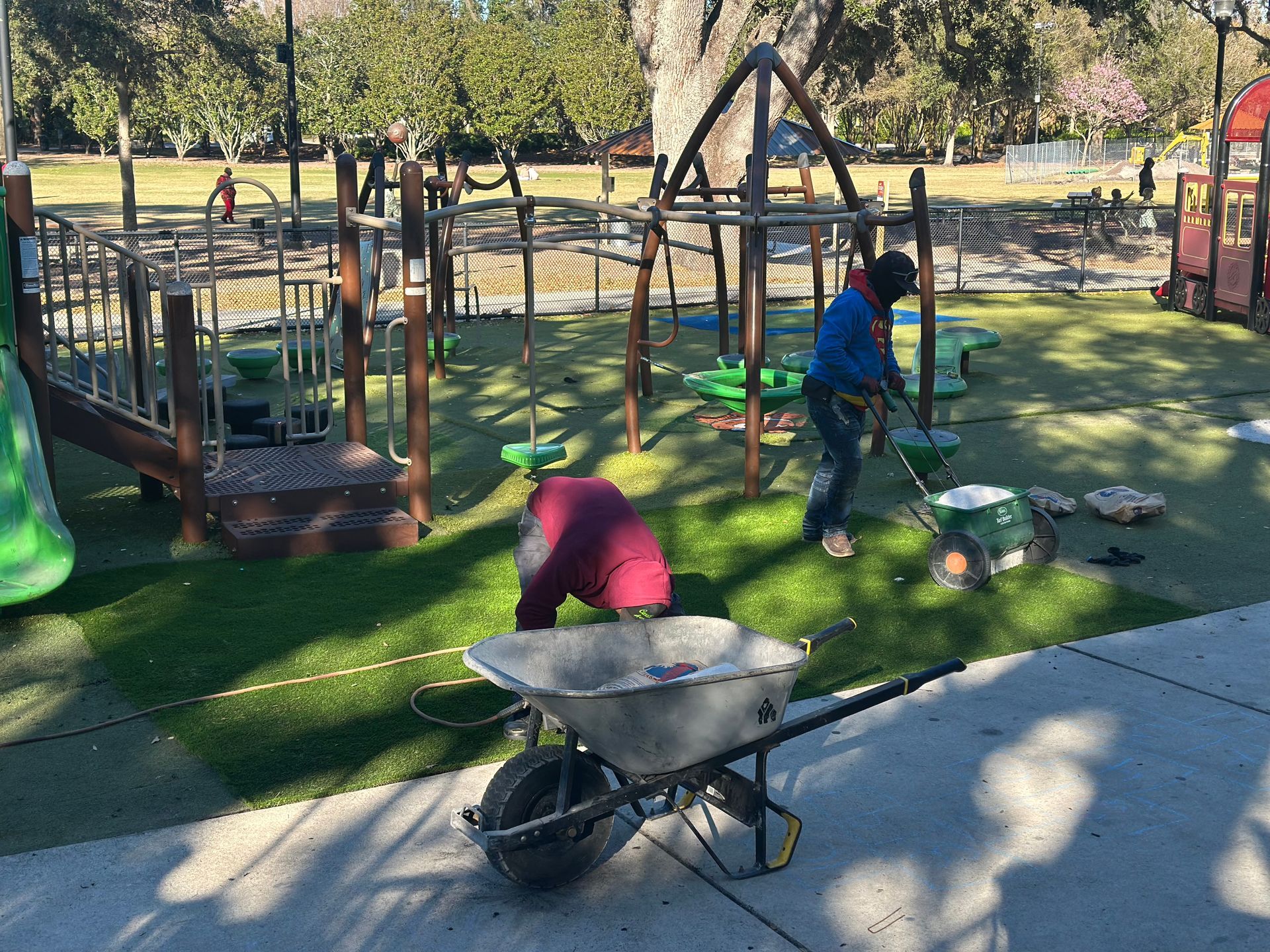 Person in green gloves rolling out sod onto prepared ground.