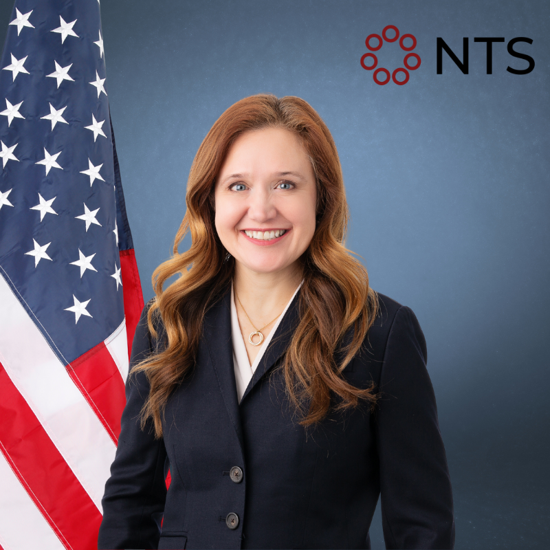 a woman in a suit is smiling in front of an american flag