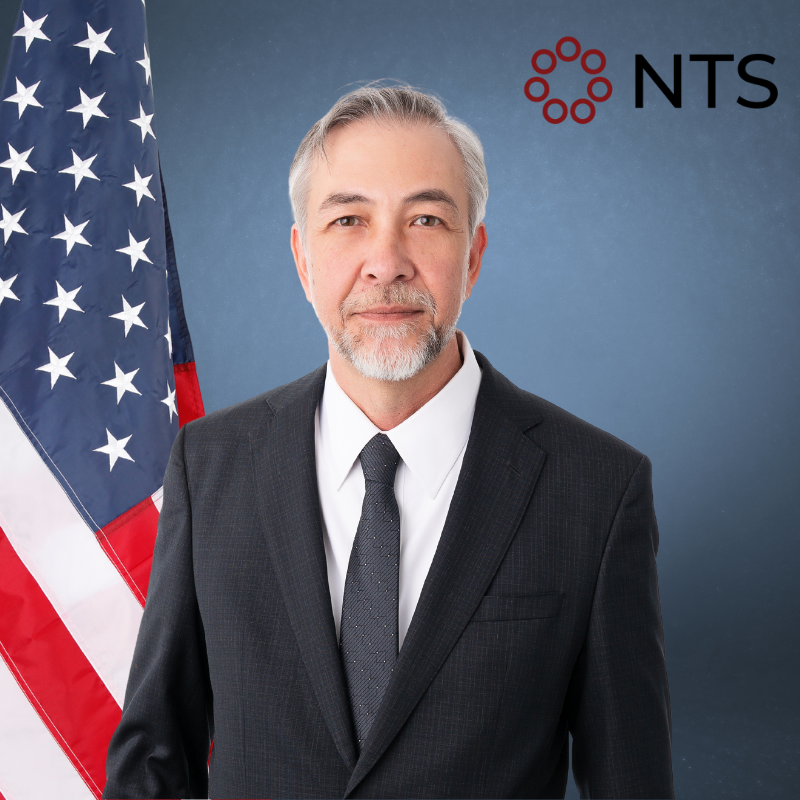a man in a suit and tie stands in front of an american flag