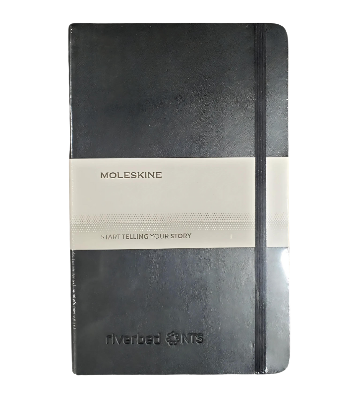 A black moleskine notebook is sitting on a white surface