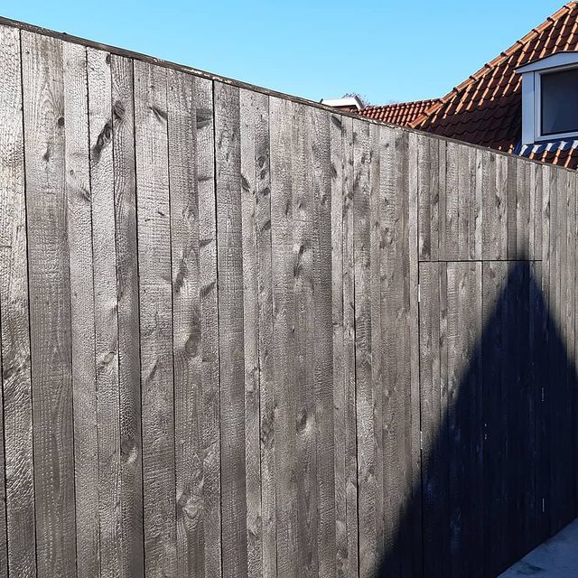 Een houten shou sugi ban wand met een huis op de achtergrond