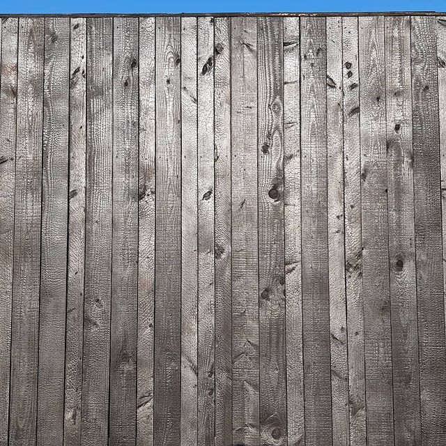 Een close-up van een houten shou sugi ban wand met een blauwe lucht op de achtergrond.