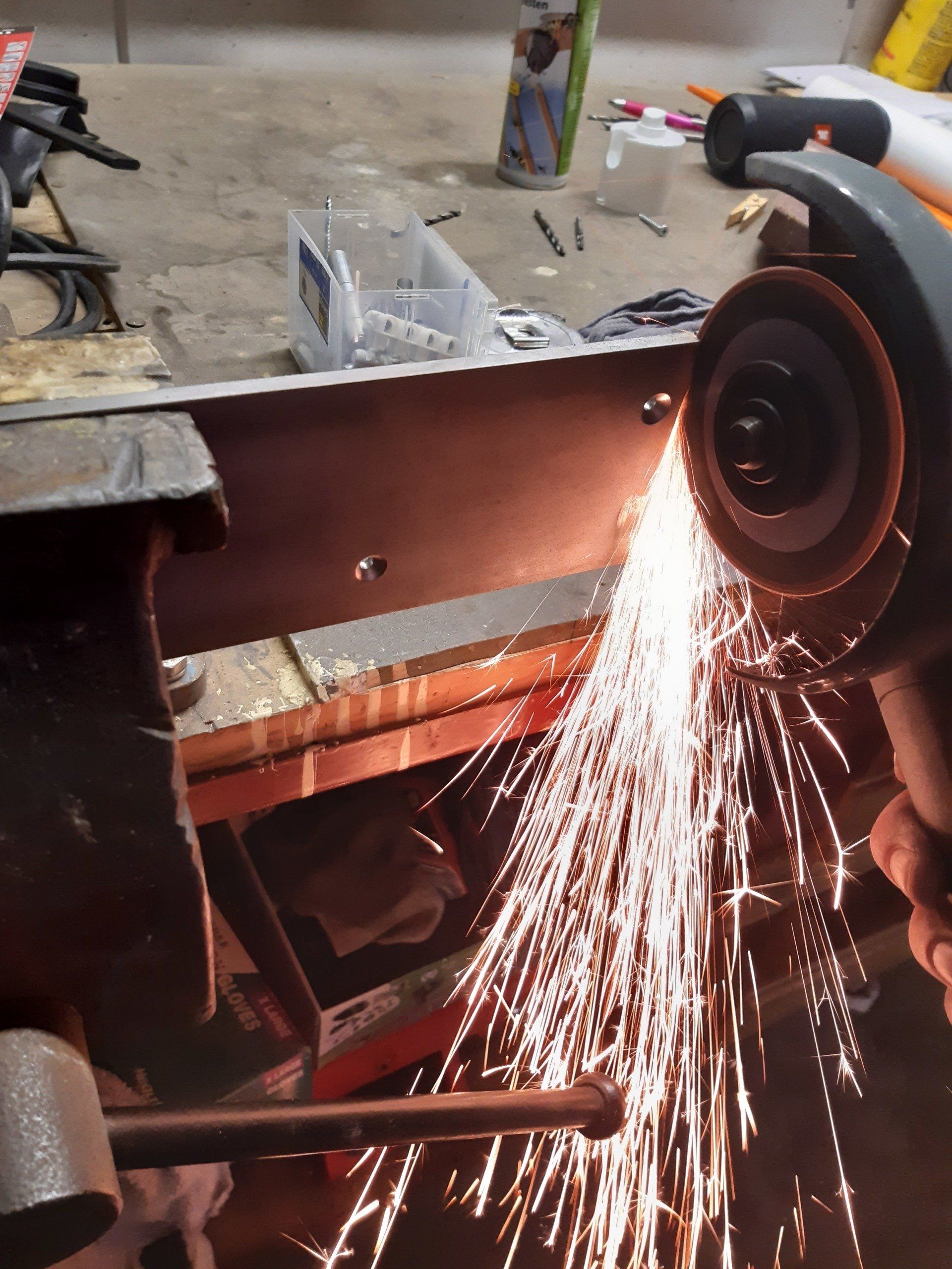 Een persoon gebruikt een slijpmachine om een ​​stuk metaal te snijden