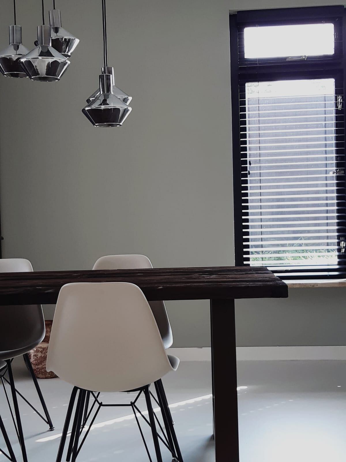 Een eetkamer met een tafel en stoelen en een raam met jaloezieën