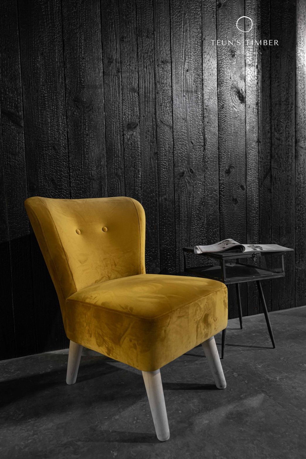 Een gele stoel staat voor een zwarte shou sugi ban muur naast een tafel.