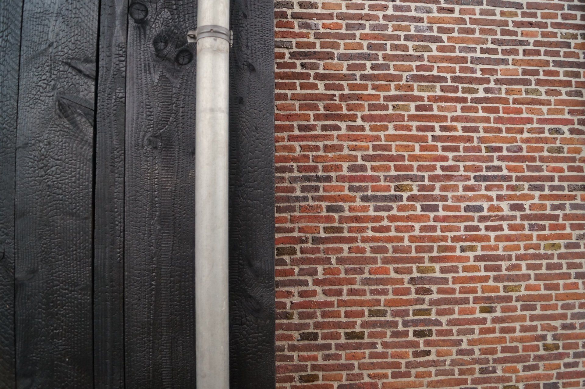 Een close-up van een bakstenen muur naast een houten shou sugi ban wand