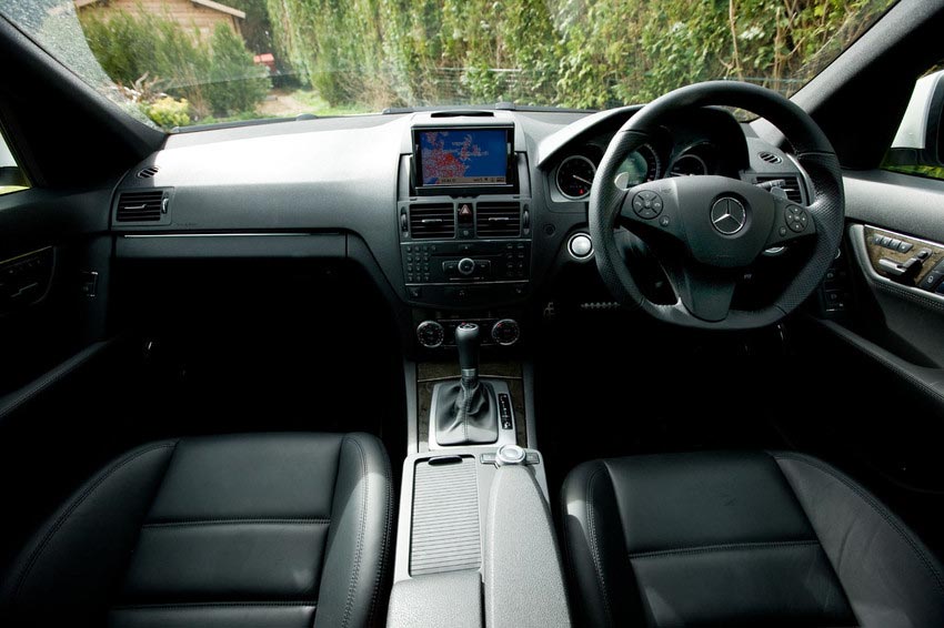 A car interior that shows its seats, steering wheel, and the hand brake.