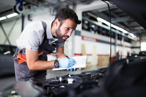 A mechanic with a clipboard is looking for engine faults on a Mercedes Benz