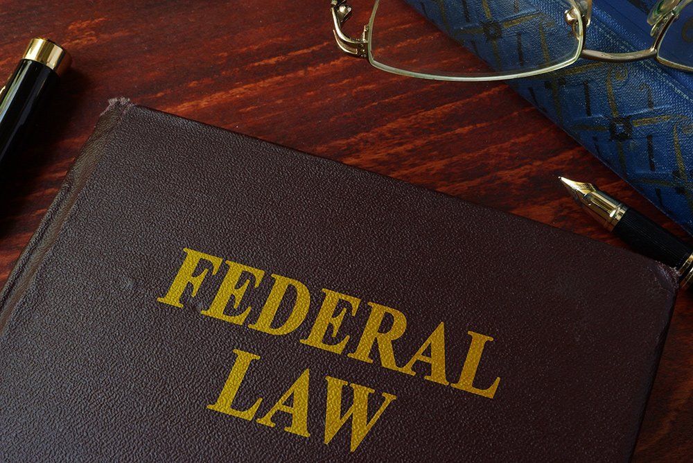 A book titled federal law is on a table next to a pen and glasses