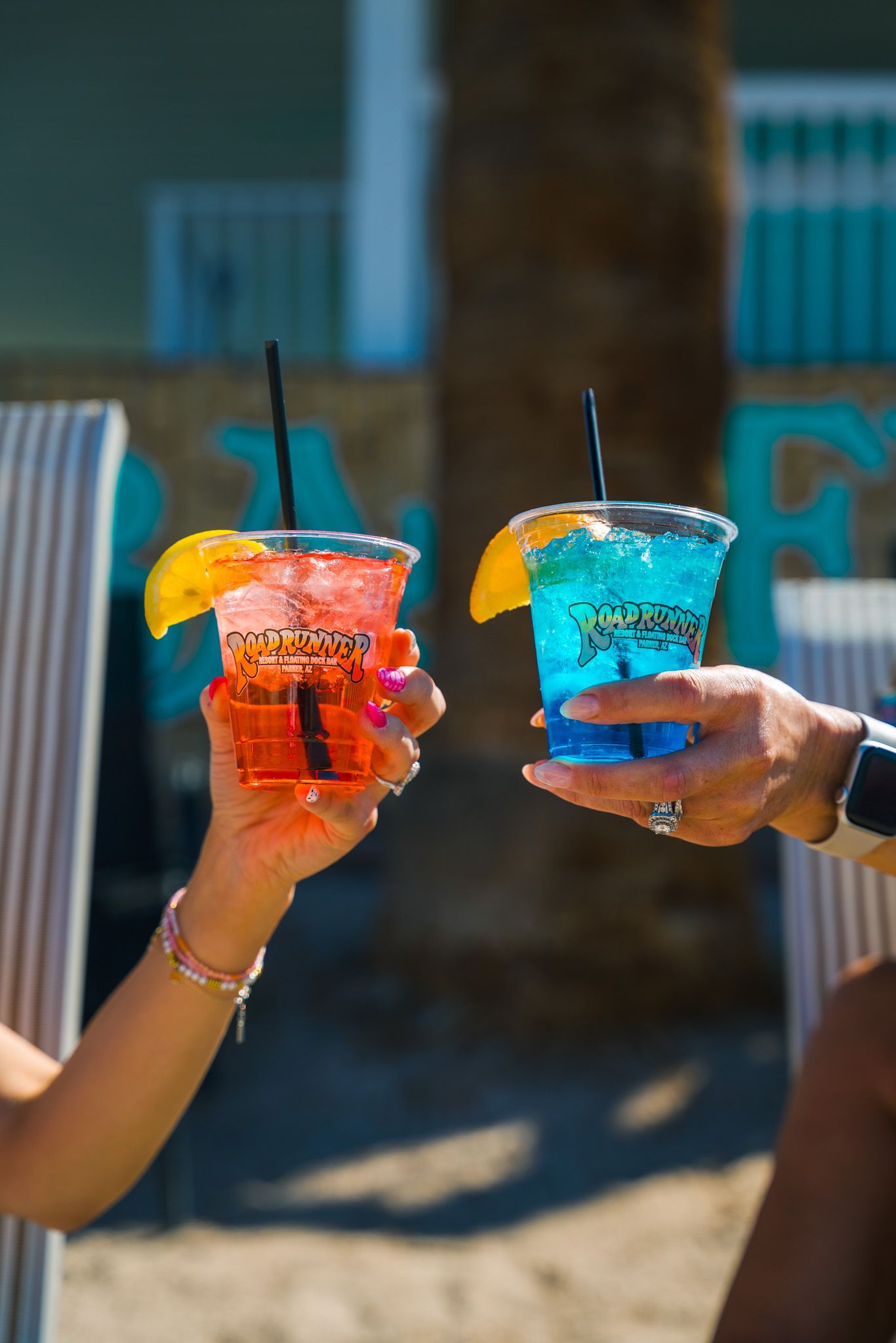 A man and a woman are toasting with drinks on the beach.