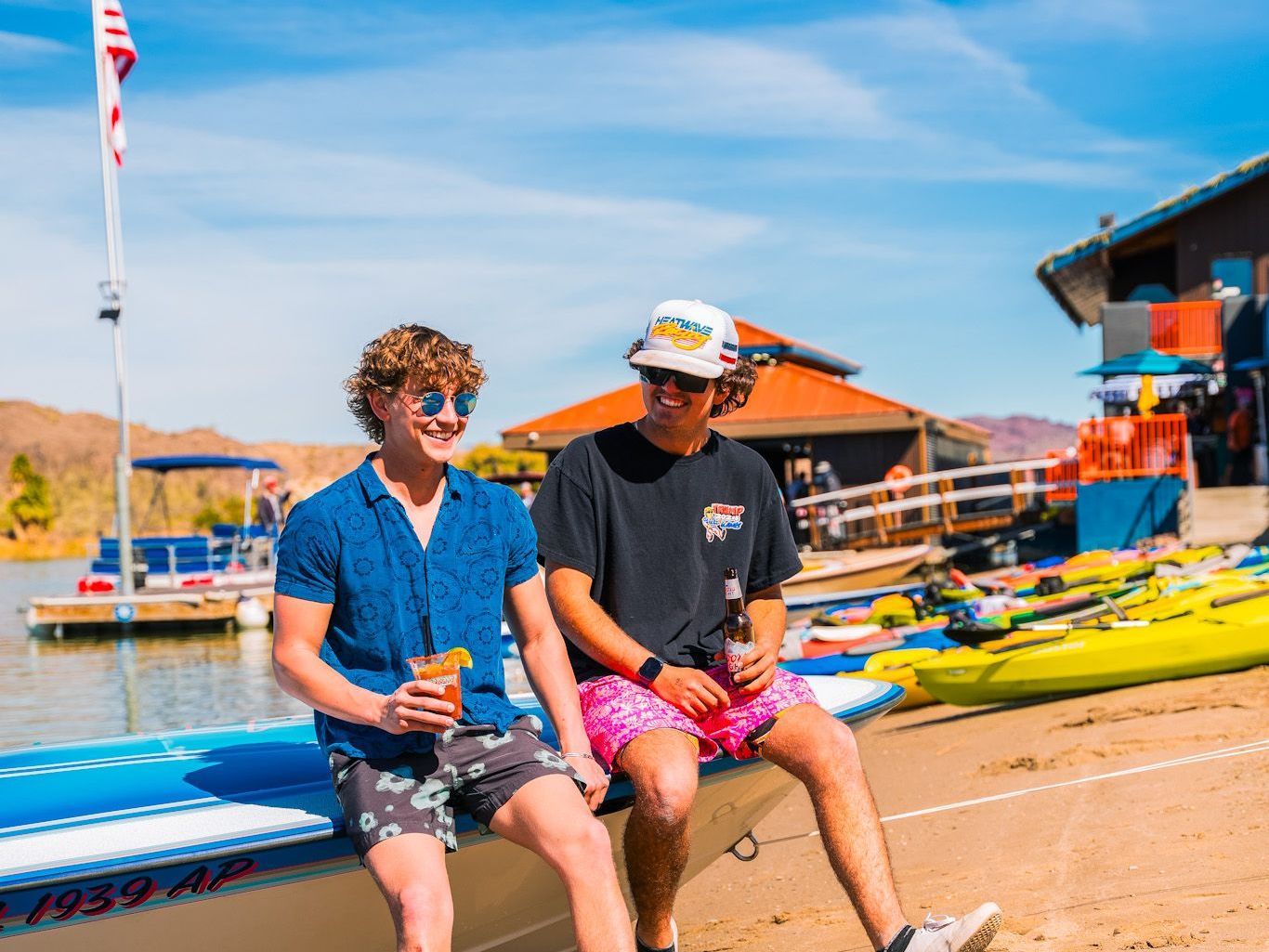 Two young men are sitting on the side of a boat.
