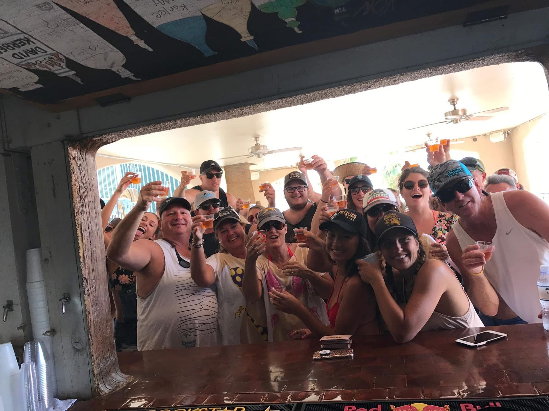 A group of people are standing around a bar holding drinks.