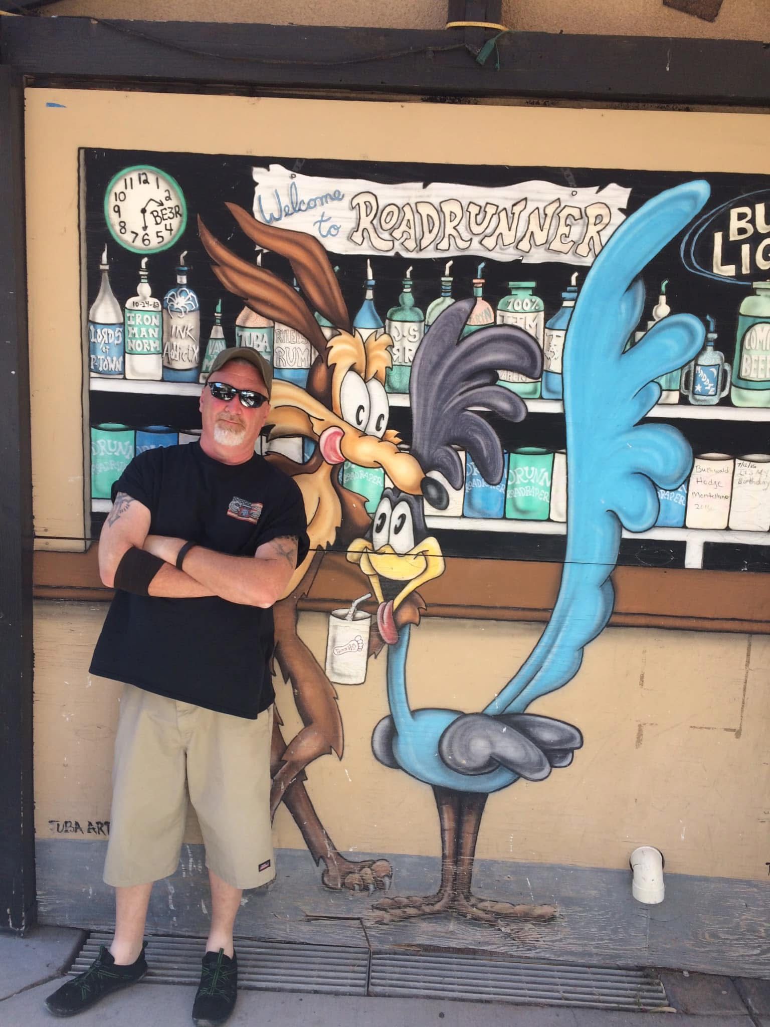 A man stands in front of a mural of coyote and road runner