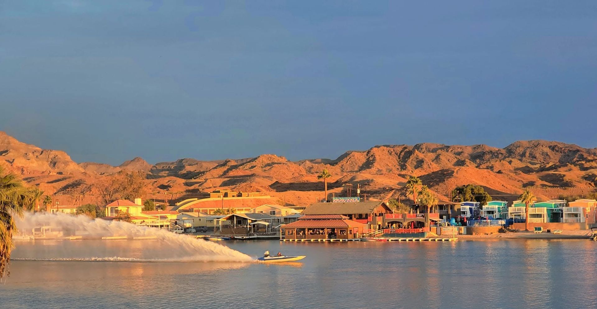 A boat is floating on top of a lake with mountains in the background.