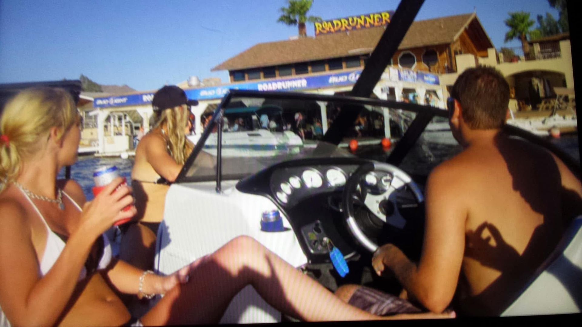 A group of people are sitting on a boat in front of a building that says paradise