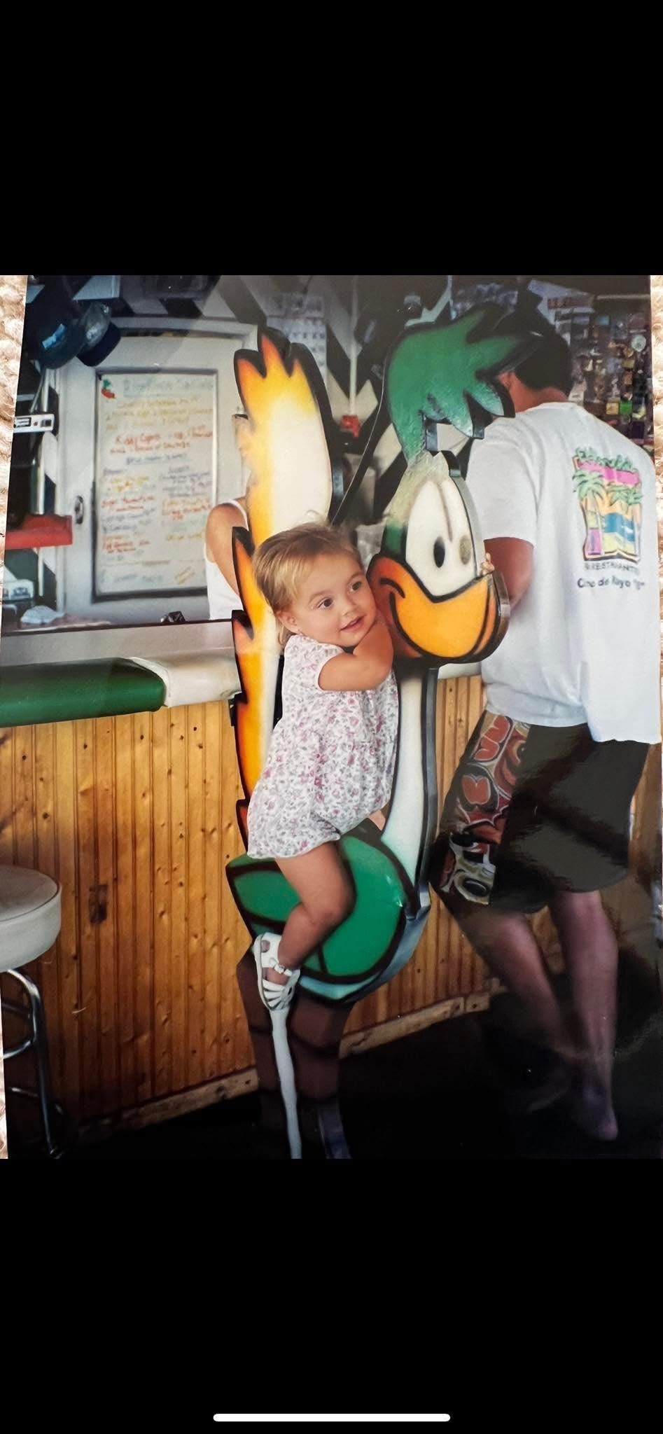 A little boy is sitting on a statue of a cartoon character.