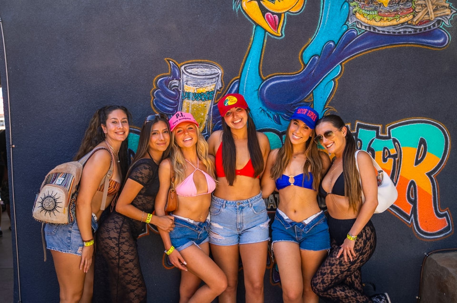 A group of women are posing for a picture in front of a graffiti wall.