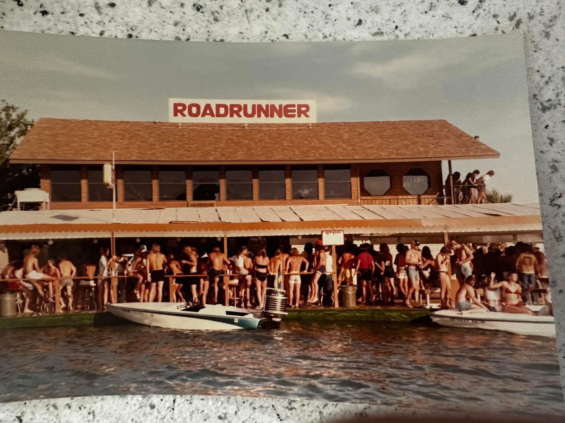 A group of people are gathered in front of a building that says roadrunner